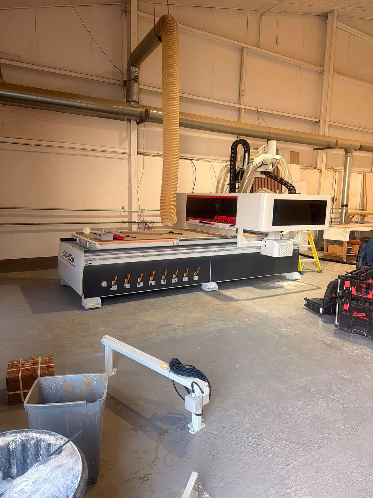 A Hua Hua CNC router in a workshop unit with its extraction hose running to the ceiling