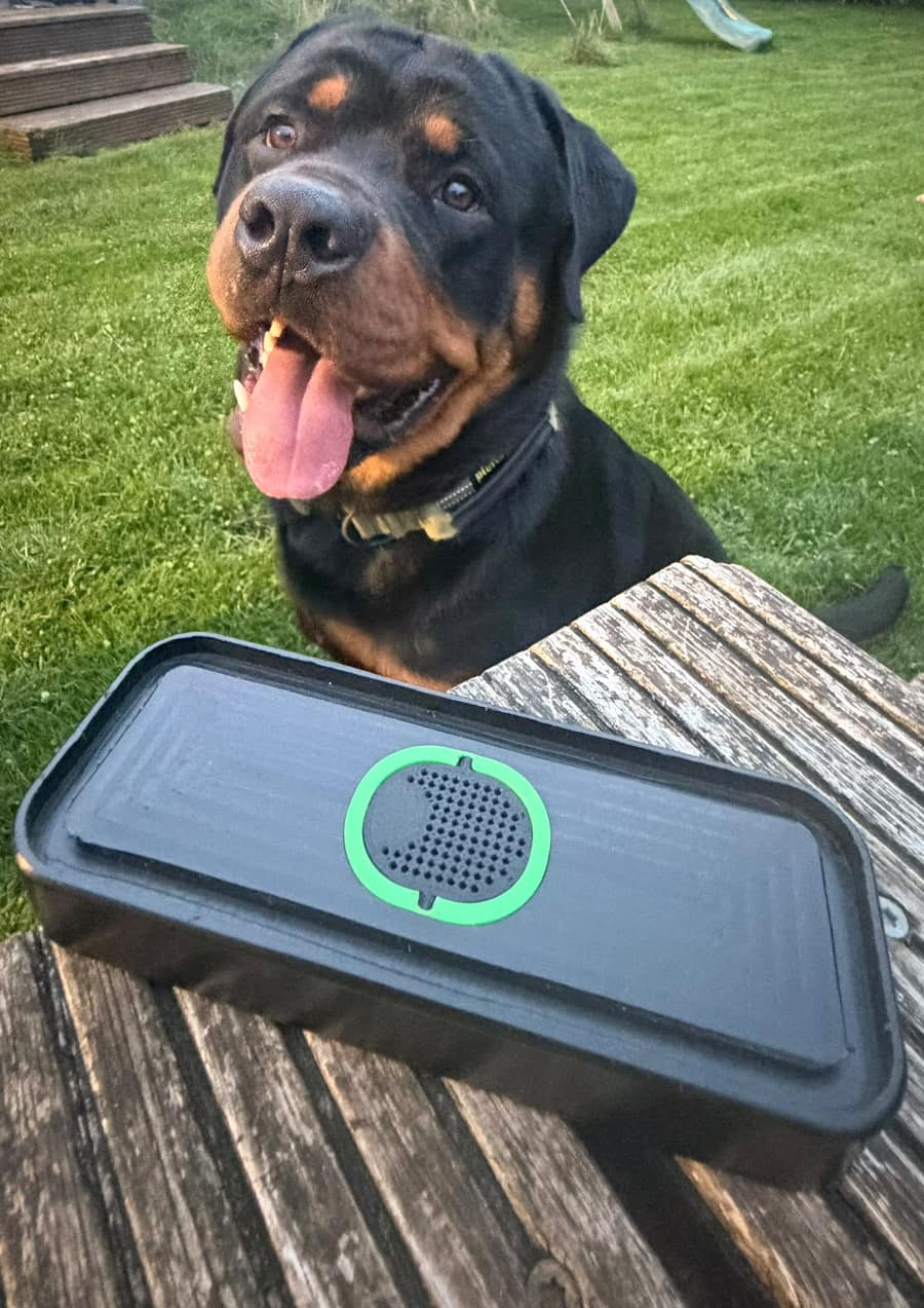 Frank the Rottweiler sitting on the grass behind a black CNC Medic vacuum pod with a green rubber sealing strip