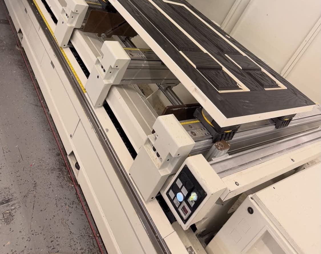 A composite door held flat on a CNC machine by vacuum pods